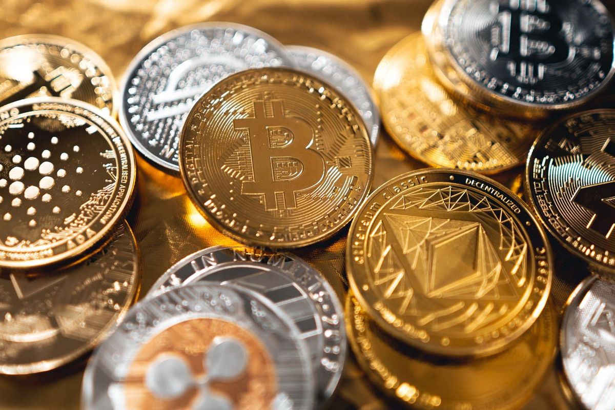 Various cryptocurrency coins, including Bitcoin and Ethereum, on a reflective surface.