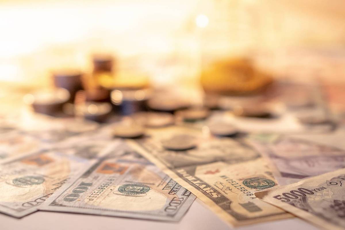 Various currency notes and coins scattered on a surface under warm lighting.