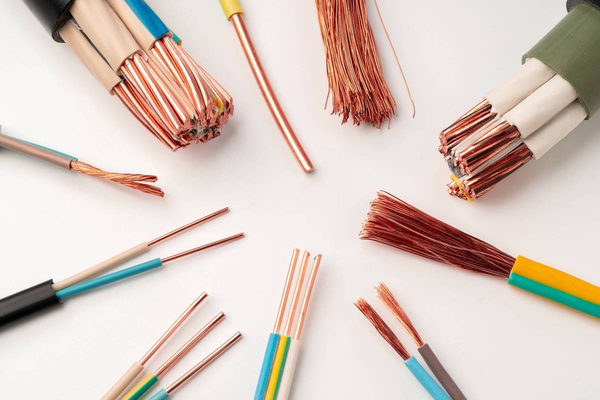 Various multicolored electrical cables with exposed copper wires spread out on a white surface.
