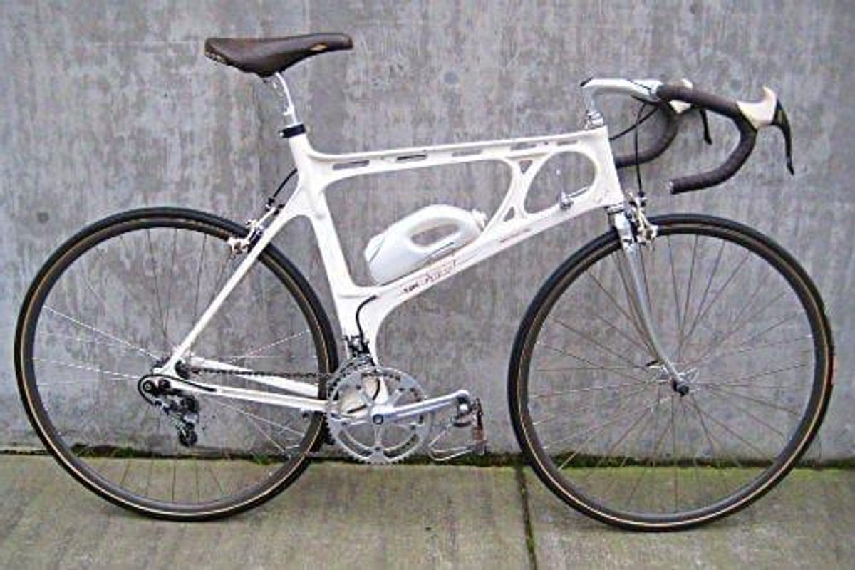 white bike on a concrete sidewalk against a concrete wall