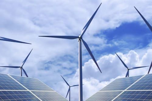 wind turbines on a cloudy day with solar panels along the bottom of the image
