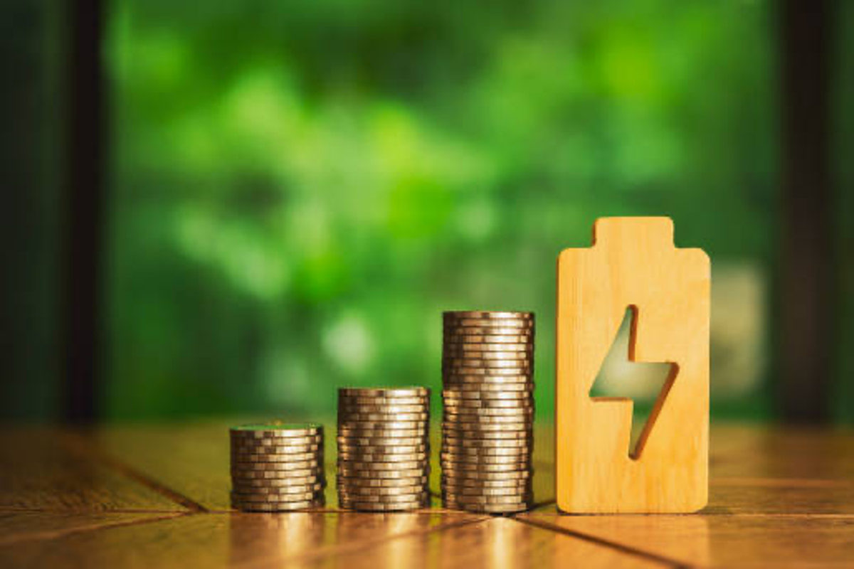 Wooden battery cutout beside stacks of coins.