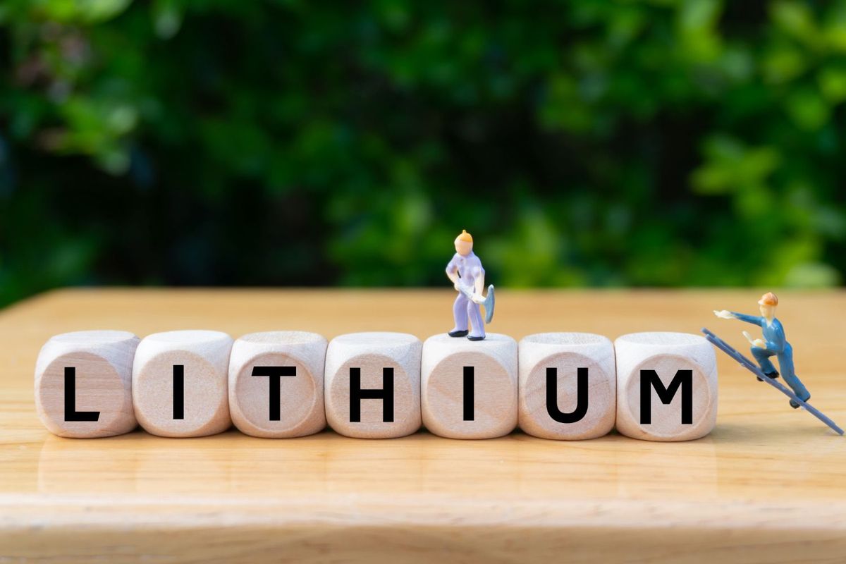 Wooden blocks spell "lithium" with mini figures mining and scaling.