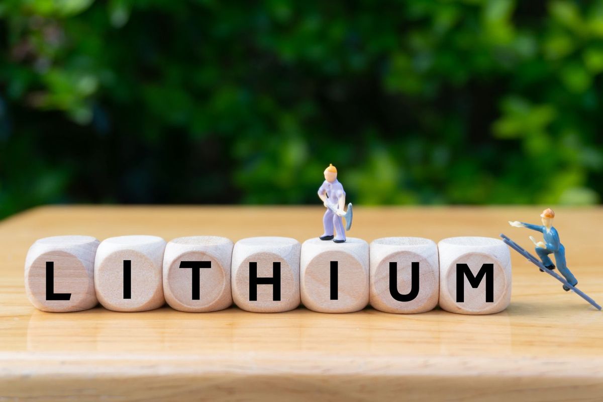 Wooden blocks spell "lithium" with mini figures mining and scaling.