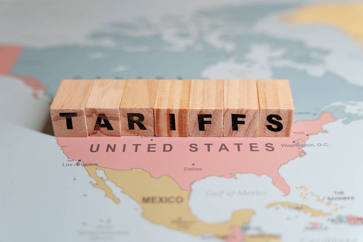 Wooden blocks spelling "TARIFFS" rest on a map displaying the United States in pink.
