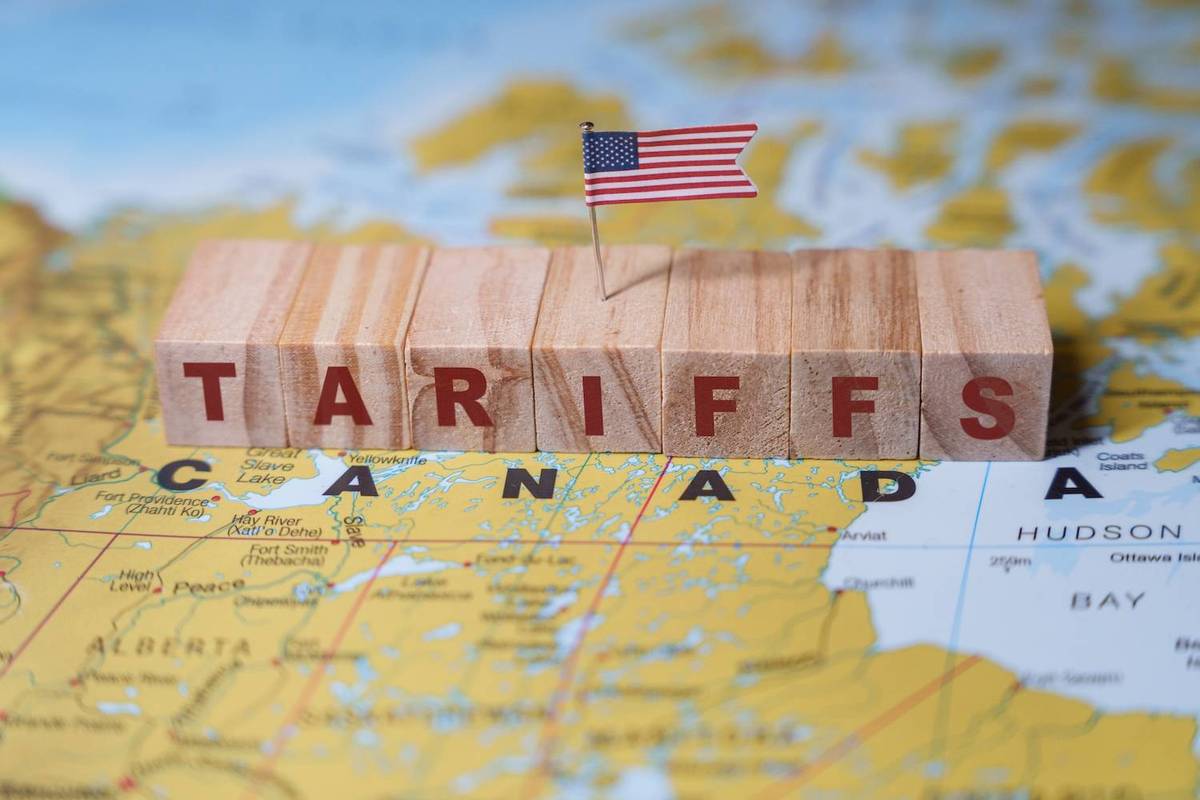 Wooden blocks spelling "TARIFFS" with a U.S. flag are placed over a map of Canada.