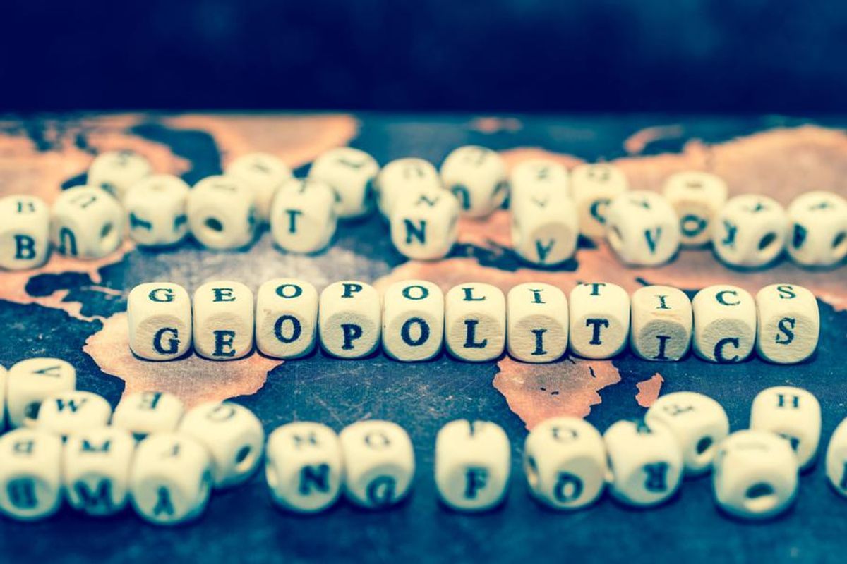 wooden dice with letters reading "geopolitics" on a map of the world