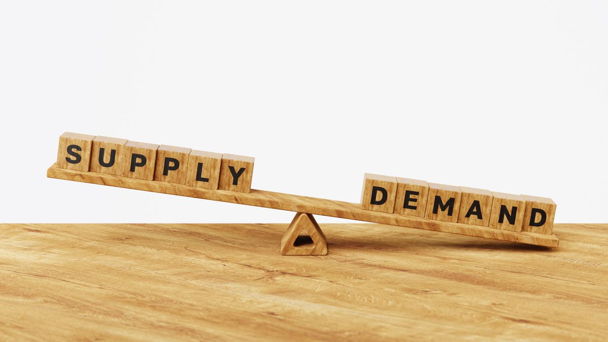 Wooden seesaw with "SUPPLY" higher than "DEMAND" spelled on blocks.