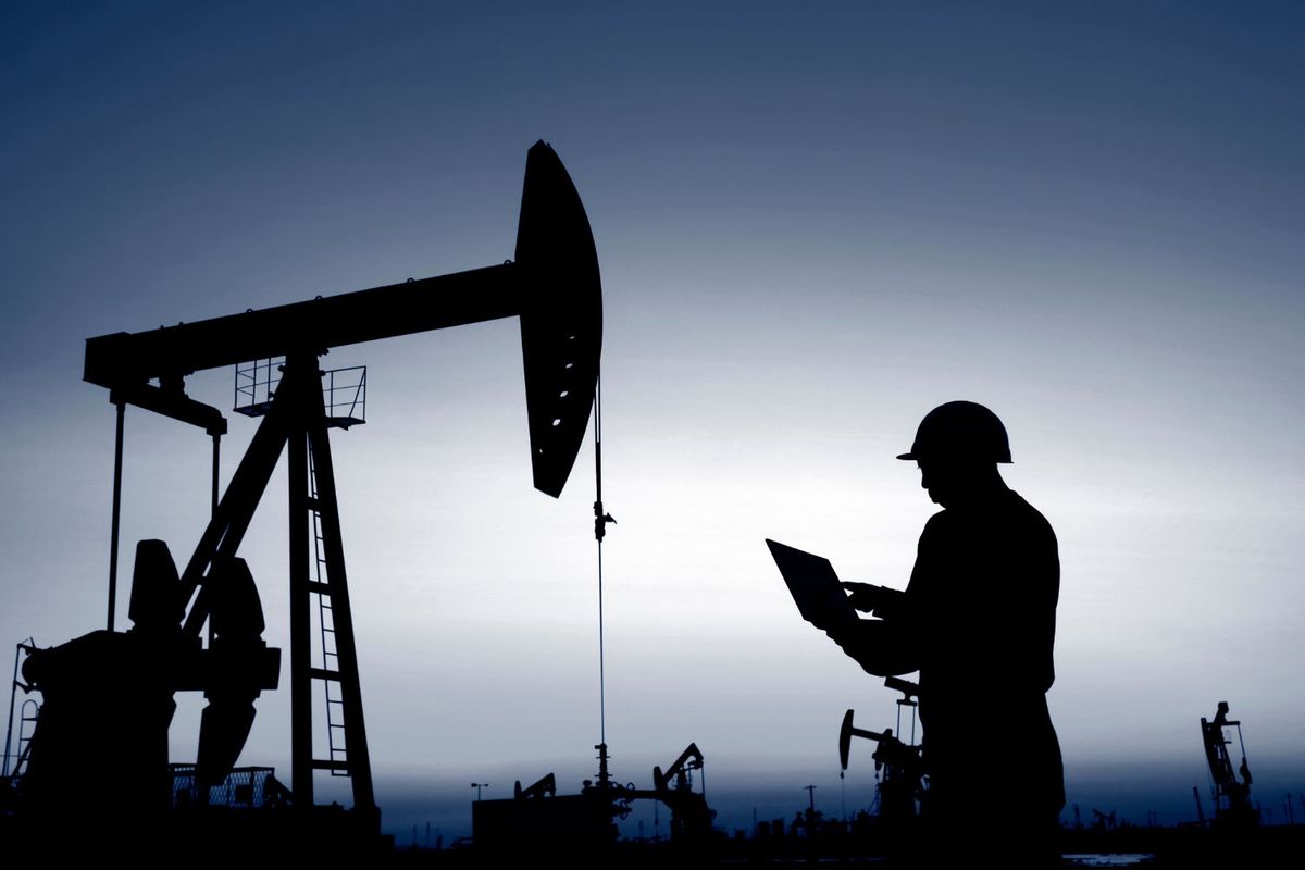 Worker beside oil rig.