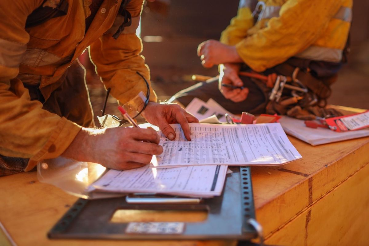 Workers in safety gear reviewing paperwork on a construction site.
