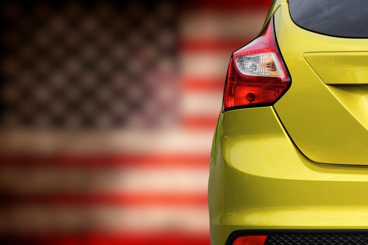 Yellow car in front of US flag.